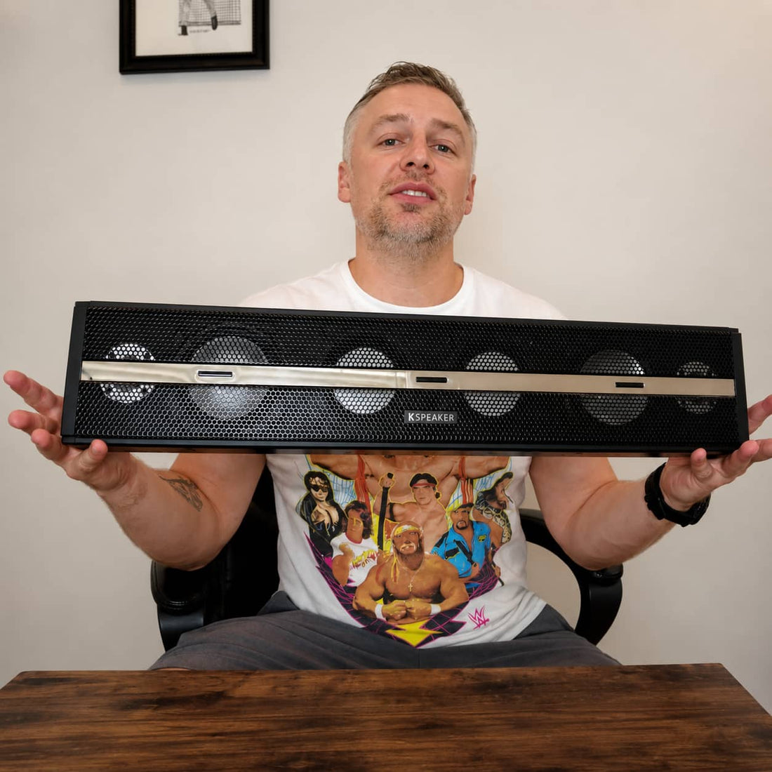 Man unboxing and holding the new heavy-duty KSPEAKER UTV soundbar off-road audio system in a studio setting.