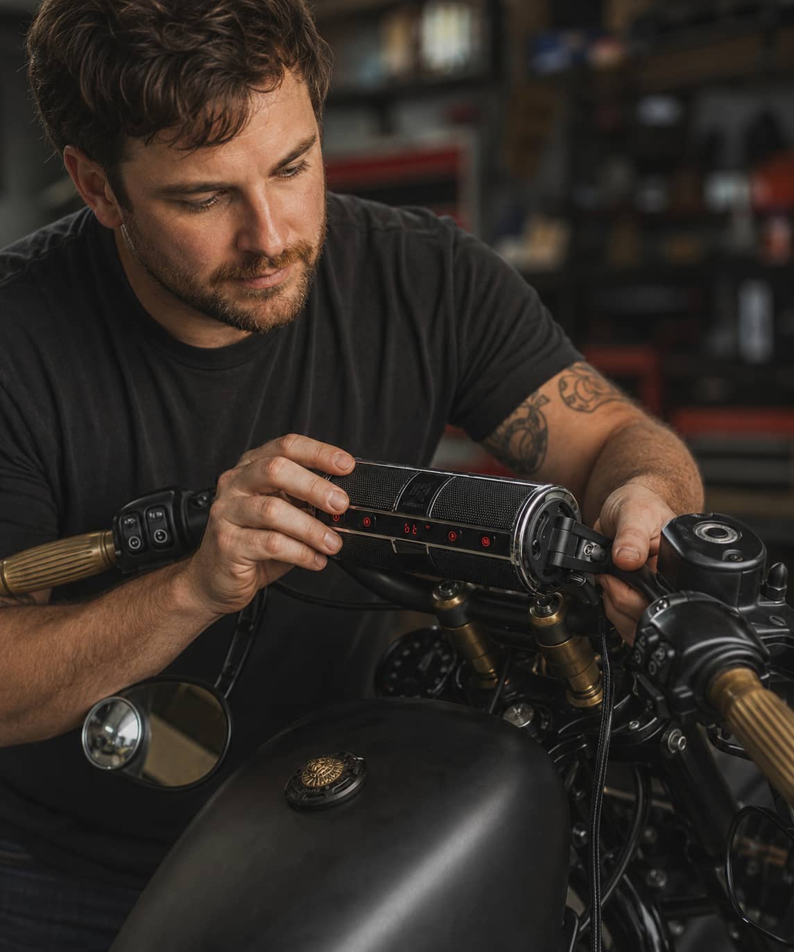 A man easily installing the KSPEAKER Bluetooth audio system onto his motorcycle handlebars in a garage.